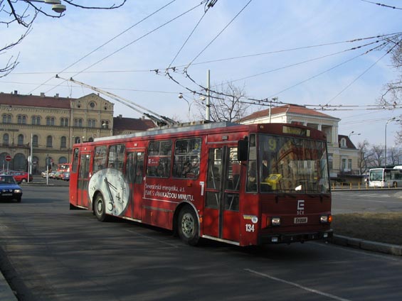 Reklamní trolejbus s nádražní budovou v pozadí.