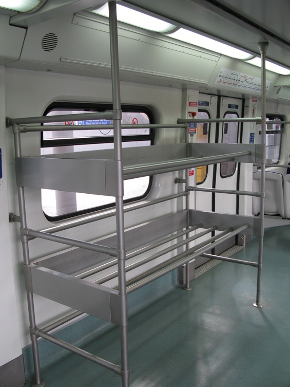 Interiér letištního metra s úložným prostorem na zavazadla. Cesta pøímo do centra Atén trvá zhruba 40 minut. Spoleèný úsek s železnicí je povrchový, poté je tato linka vedena v podzemí.
