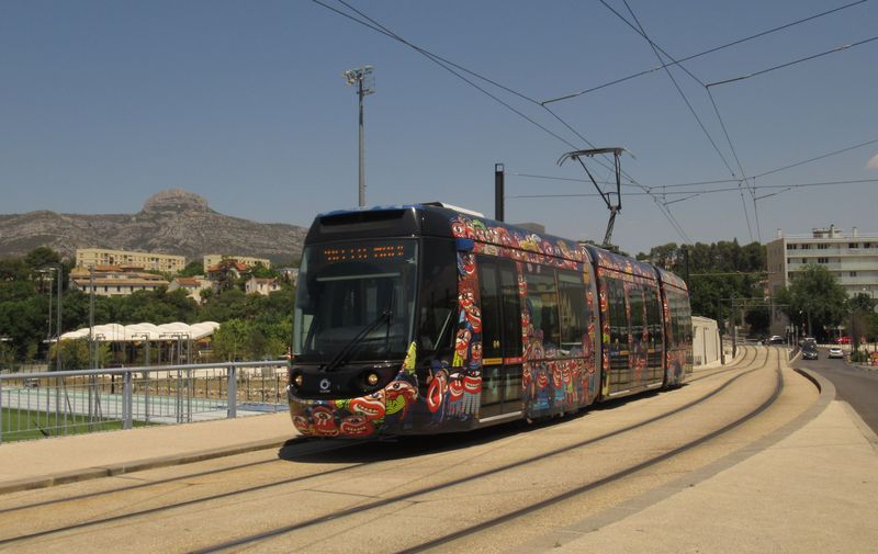 Tramvaj pokraèuje od nádraží jihozápadním smìrem kolem zdejších sportoviš�. V pozadí jsou místní vyprahlé kopce, které jsou typické pro celou oblast èlenitého Azurového pobøeží kolem Marseille.