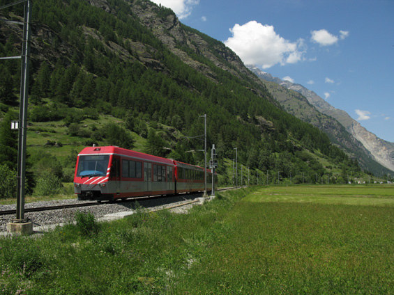 Täsch: Novìjší èásteènì bezbariérový vlak železnice Matterhorn Gotthard Bahn pøijíždí do pøedposlední stanice pøed Zermattem. Železnice sem šplhá od údolí øeky Rhony údolím øíèky Vispa.