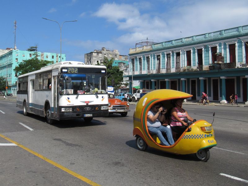 Pùvodnì korejský autobus Daewoo v závìsu za tzv. Cocotaxi, obdobou asijských tuk-tukù v centru Havany. Kvùli prastarým osobním i nákladním ojetinám zde výfukové plyny opravdu smrdí a na vytížených mìstských tøídách je pro zhýèkaného Evropana témìø nedýchatelno.