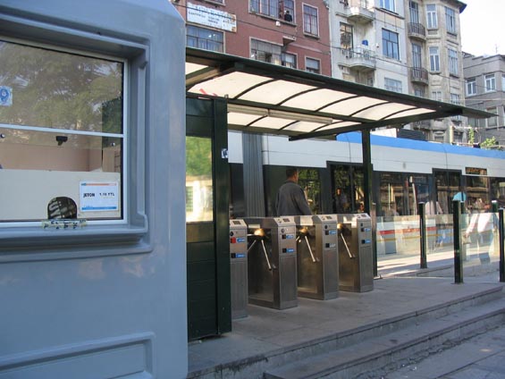 Turnikety na tramvajové zastávce i s prodejnou jízdenek, tedy žetonù.