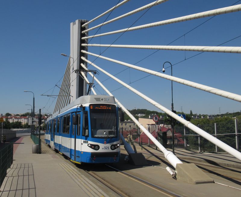 Ex-düsseldorfská tramvaj na novém pøemostìní železnièní trati se zastávkou pøímo na tomto mostì nad vlakovým nádražím Plaszów. Tuto praktickou novou spojku z roku 2015 využívá také páteøní „rychlodrážní“ linka 50.