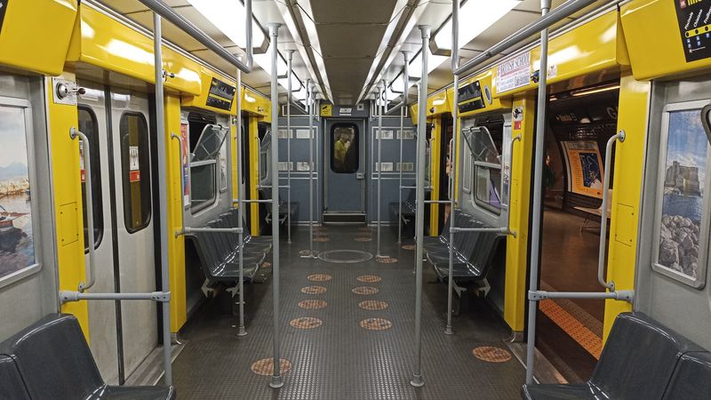 Interiér žluté linky metra s vozy stejnými jako na nìkterých linkách metra v Milánì nebo Øímì. Na podlaze jsou naznaèeny doporuèené rozestupy mezi cestujícími kvùli koronaviru. Díky dlouhým intervalùm však lze tyto rozestupy dodržet jen stìží.