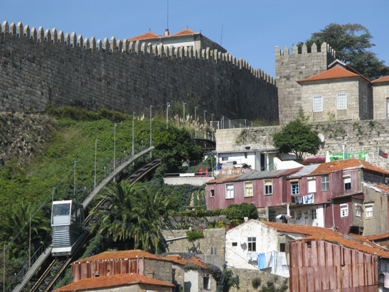 A zde již lanovka klesá podél mìstských hradeb dolù k øece Douro. Narozdíl od historických tramvají a kabinkové lanmovky na druhém bøehu zde platí pøedplatní i turistické jízdenky na MHD.
