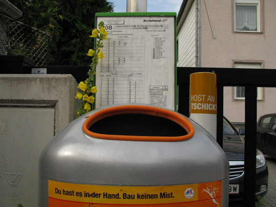 Jízdní øád autobusové linky je na tomto zastávkovém oznaèníku trochu upozadìn pøed místní kvìtenou a komunálním odpadem. Autobusové oznaèníky obecnì na okrajích Vídnì pøíliš výrazné nejsou.